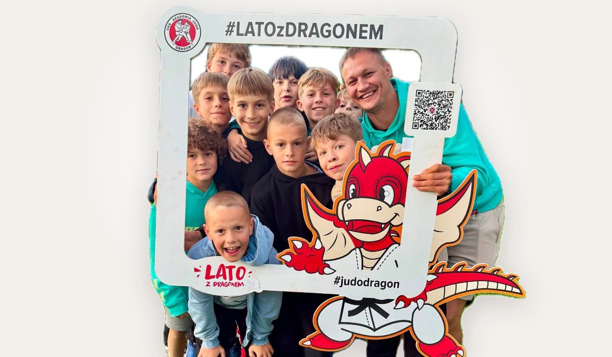 Uczestnicy Lata z Dragonem z trenerem w ramce fotobudki z maskotką klubu